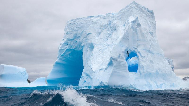 large iceberg in the ocean with waves crashing
